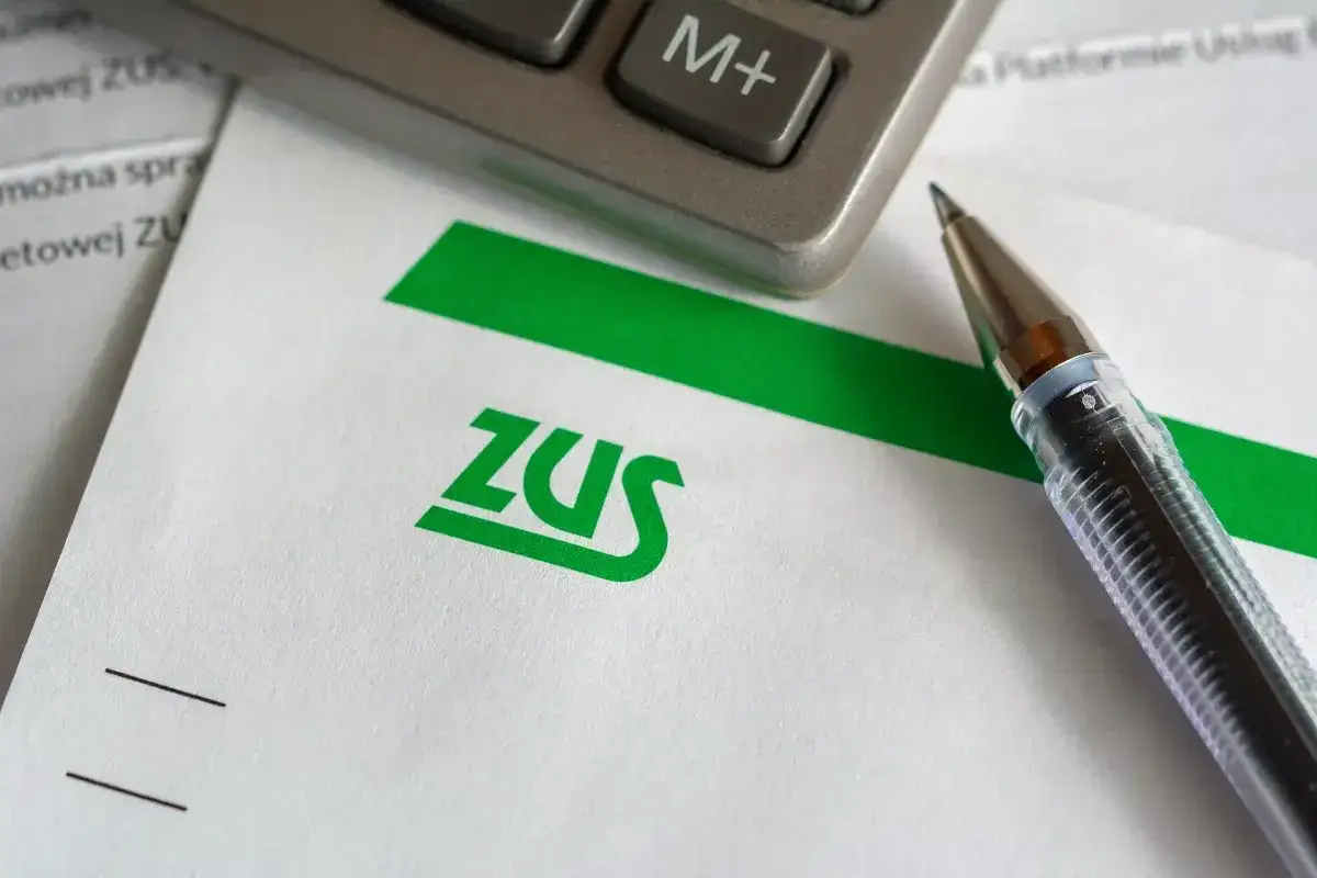 Długopis i kalkulator na dokumencie ZUS. Czy emeryt może ubezpieczyć dorosłe dziecko? Sprawdźmy!