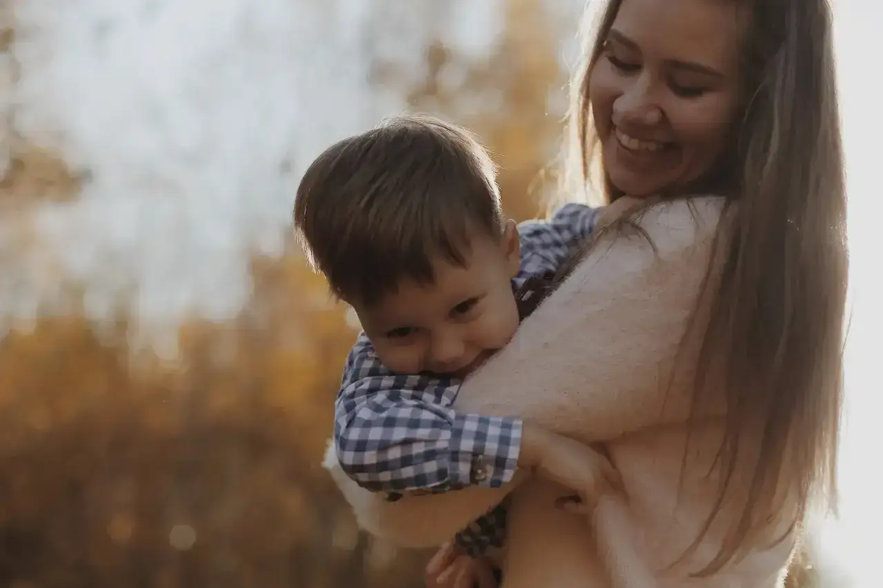 Uśmiechnięta mama tuli swoje drugie dziecko. 1000 zł na drugie dziecko to wsparcie dla takich rodzin.