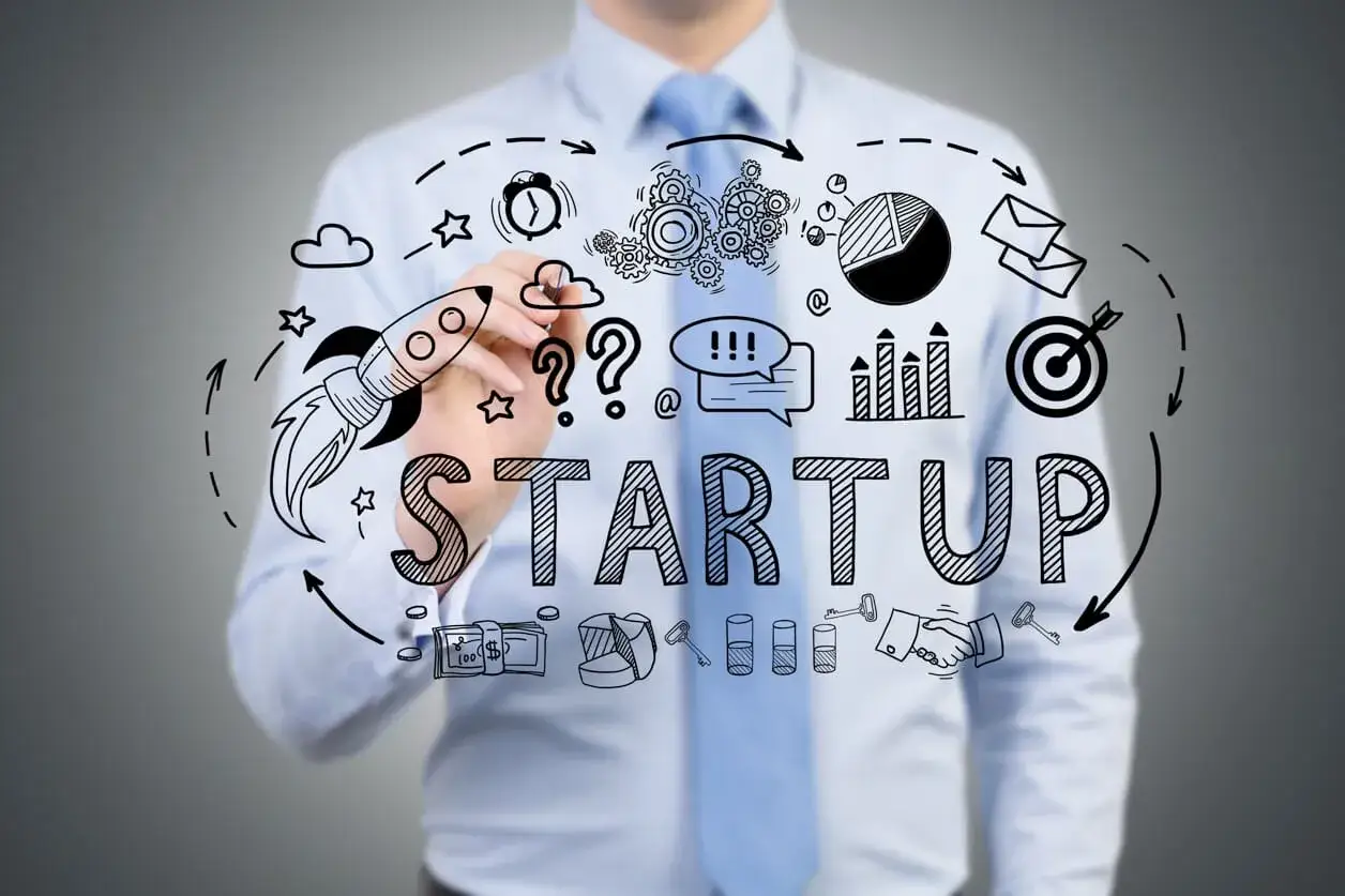 Człowiek rysuje schemat startupu: rakieta, wykresy, pieniądze, klucze. Własną działalność co się opłaca, to cel.
