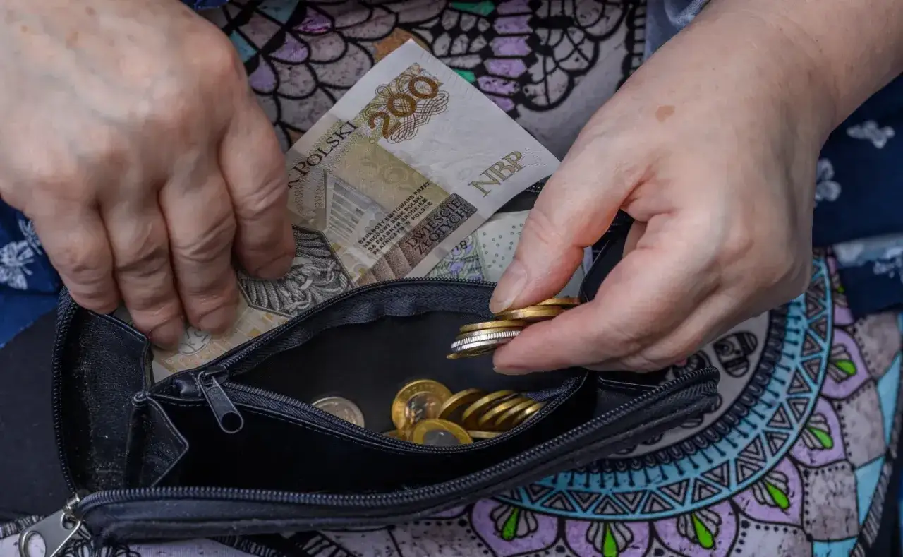 Ręce wkładają polskie banknoty i monety do portmonetki. Czy dodatek pielęgnacyjny jest opodatkowany?