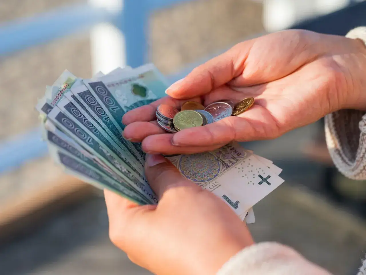 Dłonie trzymające banknoty i monety. To może być darowizna dla dziecka na spełnienie marzeń.