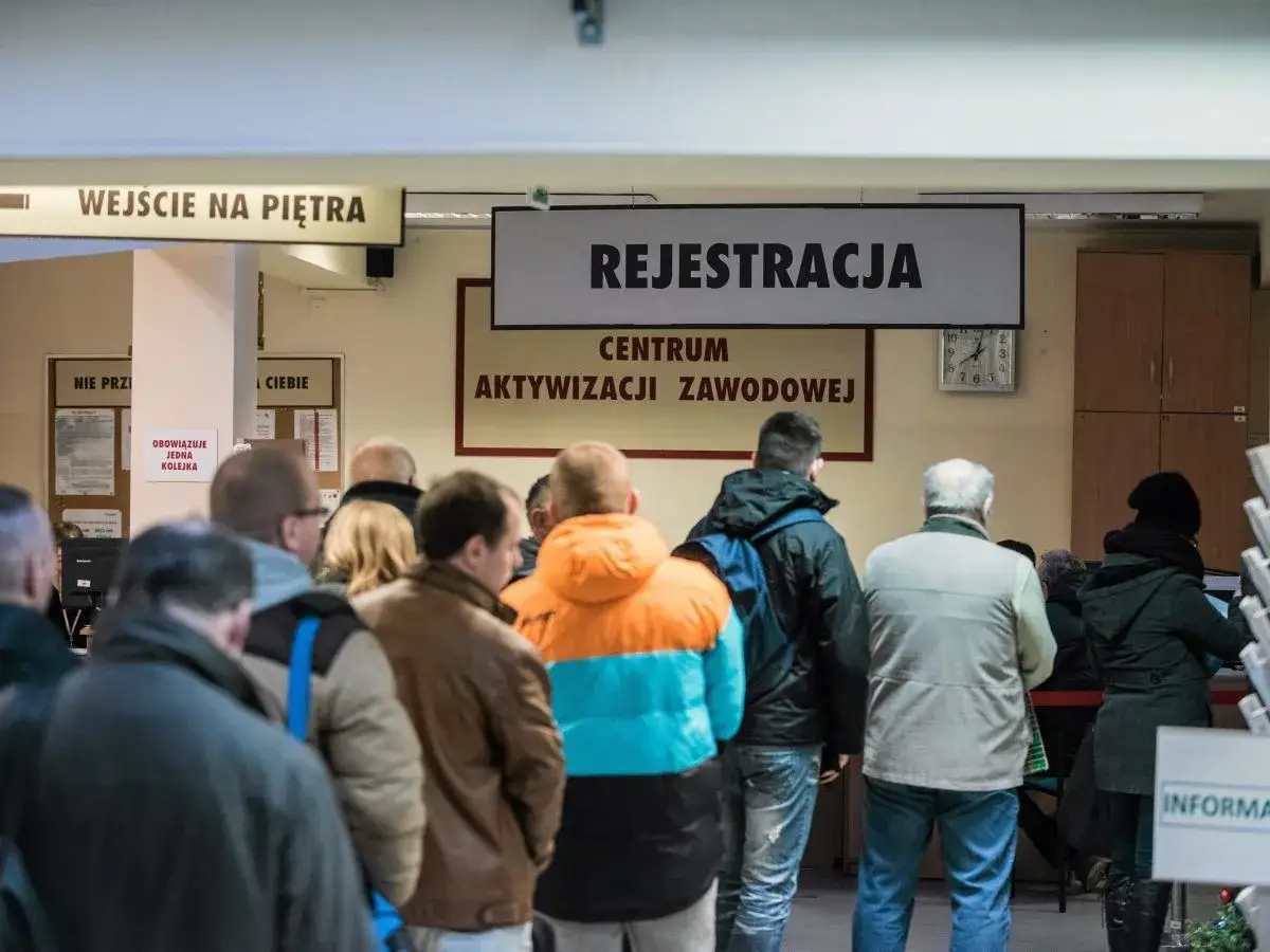 Ludzie stoją w kolejce do rejestracji w Centrum Aktywizacji Zawodowej. Dowiedz się, jak się zwolnić, żeby dostać zasiłek dla bezrobotnych.