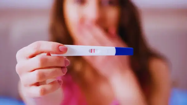 Kobieta trzyma test ciążowy z dwoma kreskami. Zastanawia się, ile wynosi l4 w ciąży i jakie są związane z tym świadczenia.